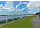 Scenic waterfront view with a walking path, lush green grass, and metal barriers along the water's edge at 7632 Plantation Cir, Bradenton, FL 34201