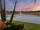 Backyard at dusk with lake view featuring fountain, lush landscaping, and colorful sky at 8271 Redonda Loop, Lakewood Ranch, FL 34202