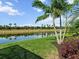 Scenic backyard view with lush green grass, landscaping, and serene lake in the background at 8271 Redonda Loop, Lakewood Ranch, FL 34202