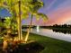 Backyard at dusk with lake view featuring fountain, lush landscaping, and warm lighting at 8271 Redonda Loop, Lakewood Ranch, FL 34202
