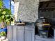 Outdoor kitchen features sleek gray cabinets, granite countertops, stone backsplash, and a premium ceramic grill at 8271 Redonda Loop, Lakewood Ranch, FL 34202