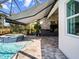 The screened-in pool features a jacuzzi, an outdoor kitchen, travertine pavers, and a retractable awning at 8271 Redonda Loop, Lakewood Ranch, FL 34202