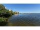 Scenic waterfront view with calm water, lush greenery, and a condo building against a clear blue sky at 8764 Midnight Pass Rd # A301, Sarasota, FL 34242