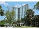 Modern high-rise condo building exterior with blue glass, white trim, and lush landscaping at 1111 N Gulfstream Ave # 8D, Sarasota, FL 34236