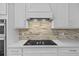 Modern kitchen with stainless steel cooktop, backsplash, and white cabinetry at 11419 Gallatin Trl, Parrish, FL 34219