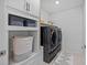 Modern laundry room featuring a new washer and dryer set with custom shelving and white shiplap wall at 11419 Gallatin Trl, Parrish, FL 34219