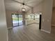 The living room with wood-look flooring, a ceiling fan, and sliding glass doors that open to the pool and kitchen at 4509 30Th Street E Cir, Bradenton, FL 34203