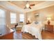 Comfortable bedroom with a ceiling fan, tray ceiling, and abundant natural light from large windows at 5020 Savona Run, Bradenton, FL 34211