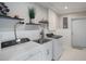 Modern laundry room with stainless steel sink, floating shelves, and a side-by-side washer and dryer at 5250 Calle De Rio, Sarasota, FL 34242