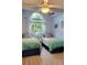 Inviting bedroom featuring two twin beds, a ceiling fan, and a bright window showcasing tropical views at 625 Duchess Blvd, Dunedin, FL 34698
