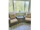 Cozy enclosed porch with seating, side table, and views of mature trees at 625 Duchess Blvd, Dunedin, FL 34698