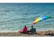 Relaxing beach scene with couple enjoying the ocean view under a colorful umbrella at 721 Cadiz Rd, Venice, FL 34285