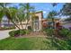 Charming home's entrance highlighted by lush landscaping, palm trees, and a brick-accented facade at 7911 Kavanagh Ct, Sarasota, FL 34240