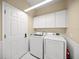 Bright laundry room with modern washer and dryer units and storage cabinets at 7911 Kavanagh Ct, Sarasota, FL 34240