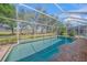 Screened-in pool and spa with a brick surround overlooking a lush green yard at 7911 Kavanagh Ct, Sarasota, FL 34240