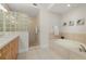 Well-lit bathroom with a glass block shower and a large soaking tub with tile surround at 147 Tampa E Ave # 702, Venice, FL 34285