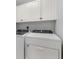 Laundry room with white front load washer and dryer and white upper cabinets at 147 Tampa E Ave # 702, Venice, FL 34285