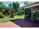 A tranquil backyard boasts a brick patio, screened-in porch and lush landscaping at 1555 Flower Dr, Sarasota, FL 34239