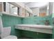 Bathroom featuring green tiled walls and floor with sink and toilet at 1555 Flower Dr, Sarasota, FL 34239