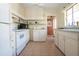 A bright kitchen features white cabinets and appliances, and tile flooring at 1555 Flower Dr, Sarasota, FL 34239