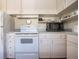 Close-up of a kitchen with white appliances and cabinets, including stove and microwave at 1555 Flower Dr, Sarasota, FL 34239