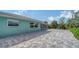 Rear exterior view of a light blue home featuring the sunroom addition and paver patio at 217 Giotto Dr, Nokomis, FL 34275