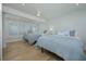 Airy bedroom showcasing two beds with blue and white bedding, complemented by a ceiling fan and shuttered windows at 231 Hourglass Way # V5, Sarasota, FL 34242