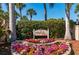 Community entrance sign that says Whispering Sands, surrounded by colorful flowers and lush landscaping at 231 Hourglass Way # V5, Sarasota, FL 34242