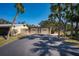 Home exterior featuring a spacious driveway leading to a two-car garage, surrounded by lush palm trees and blue sky at 231 Hourglass Way # V5, Sarasota, FL 34242