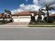 Inviting home features a terracotta roof, three-car garage, manicured landscaping, and mature palm trees at 23547 Waverly Cir, Venice, FL 34293