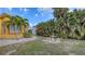 Backyard with a paver walkway, tropical landscaping, and outdoor seating area under the clear sky at 2416 Webber St, Sarasota, FL 34239