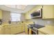 Efficient kitchen with bright yellow cabinets, a stainless steel oven, and built-in microwave at 2416 Webber St, Sarasota, FL 34239