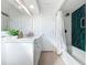 Bright bathroom featuring white vanity, framed mirror, green tiled shower, and light wood floors at 2900 Woodpine Ct, Sarasota, FL 34231