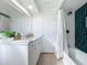 Bright bathroom featuring white vanity, framed mirror, green tiled shower, and light wood floors at 2900 Woodpine Ct, Sarasota, FL 34231
