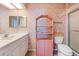 Retro-style bathroom with pink floral wallpaper, white vanity, toilet, shelving unit, and shower at 312 108Th W St, Bradenton, FL 34209