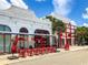 Outdoor restaurant seating featuring bright red chairs, tables, and sun umbrellas on the sidewalk at 430 Kumquat Ct # 306, Sarasota, FL 34236