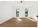 Bright bedroom with hardwood floors, ceiling fan, and two windows with treelined view at 4620 Riverview Blvd, Bradenton, FL 34209