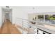 Bright hallway with hardwood floors and modern white railings overlooking the home's entrance, stairs and decorative chandelier at 4620 Riverview Blvd, Bradenton, FL 34209