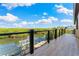 Balcony with black railing that overlooks the river with a dock, trees, and a blue, partly cloudy sky at 5236 Siesta Cove Dr, Sarasota, FL 34242