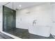 Modern bathroom featuring a walk-in shower and a standalone white bathtub with sleek fixtures and mosaic tile at 5236 Siesta Cove Dr, Sarasota, FL 34242