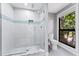 Modern bathroom featuring a glass walk-in shower with white tile and a blue accent stripe, plus a toilet and window at 5236 Siesta Cove Dr, Sarasota, FL 34242