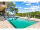 Inviting pool with patio, waterfront views, surrounded by lush landscaping and clear blue skies at 5236 Siesta Cove Dr, Sarasota, FL 34242