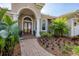 Home's arched front entrance features double doors, lush landscaping, and a brick walkway at 6922 Stanhope Pl, University Park, FL 34201