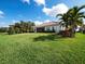 Expansive backyard with lush green grass, mature palm trees, and the home's exterior at 8284 Barton Farms Blvd, Sarasota, FL 34240