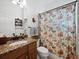 This bathroom features a wood vanity, granite countertop, patterned shower curtain, and wall shelves at 8284 Barton Farms Blvd, Sarasota, FL 34240