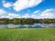 Stunning lake view with blue sky, white clouds, and lush green lawn at 8284 Barton Farms Blvd, Sarasota, FL 34240