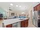 Kitchen with stainless steel appliances, brown cabinets, and an island, seamlessly flowing into dining and living areas at 9043 39Th Street E Cir, Parrish, FL 34219
