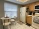 Bright kitchen with stainless appliances, white tile floors, and a quaint table and chair set by the window at 1129 Montrose Pl, Dunedin, FL 34698