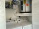 The laundry room has a white washer and dryer, shelving, and a water heater at 1129 Montrose Pl, Dunedin, FL 34698