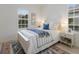 Bright bedroom featuring a large bed with blue accents, a bedside table and natural light from the windows at 11728 Strandhill Ct, Lakewood Ranch, FL 34202